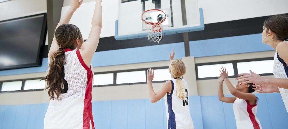 Female High School Basketball Team Shooting At Basket On Court